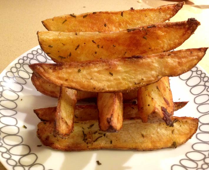Garlic Rosemary Baked Fries Recipe- are easy oven baked comfort food fun. Grab a couple of potatoes, some rosemary and garlic for a fluffy salty snack. Perfect for weeknights or holiday dinner. www.ChopHappy.comj