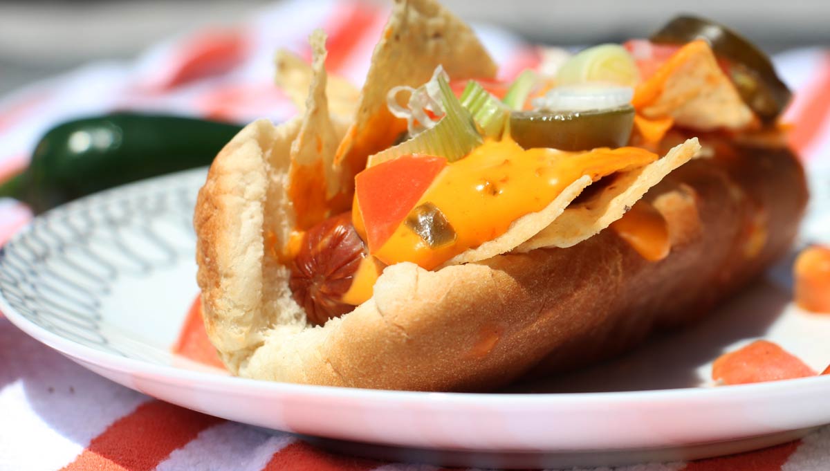 Nacho Party Dog Recipe. Grab the beef hot dog, cheddar cheese sauce, pickled jalapenos, tomatoe, and scallions. This is the perfect grilling recipe. Harpy Cooking! www.ChopHapy.com #hotdogrecipe #nachos
