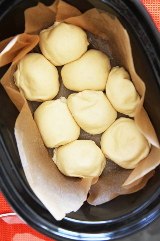 Slow Cooker Dinner Rolls Recipe - is so easy and makes more room in the oven. Grab dinner roll dough, garlic, rosemary, and a slow cooker (crock pot). This is magically awesome comfort food. www.ChopHappy.com #dinnerrolls