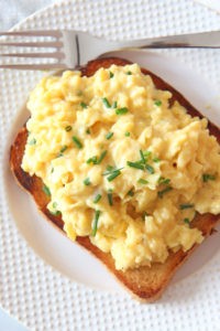 How To Make The Creamiest Scrambled Eggs. This is a perfect simple brunch, breakfast, or dinner that has very little ingredients! Grab eggs, butter, sour cream, and chives. Happy Egg Cooking! www.ChopHappy.com #howtomakescrambledeggs #eggrecipe
