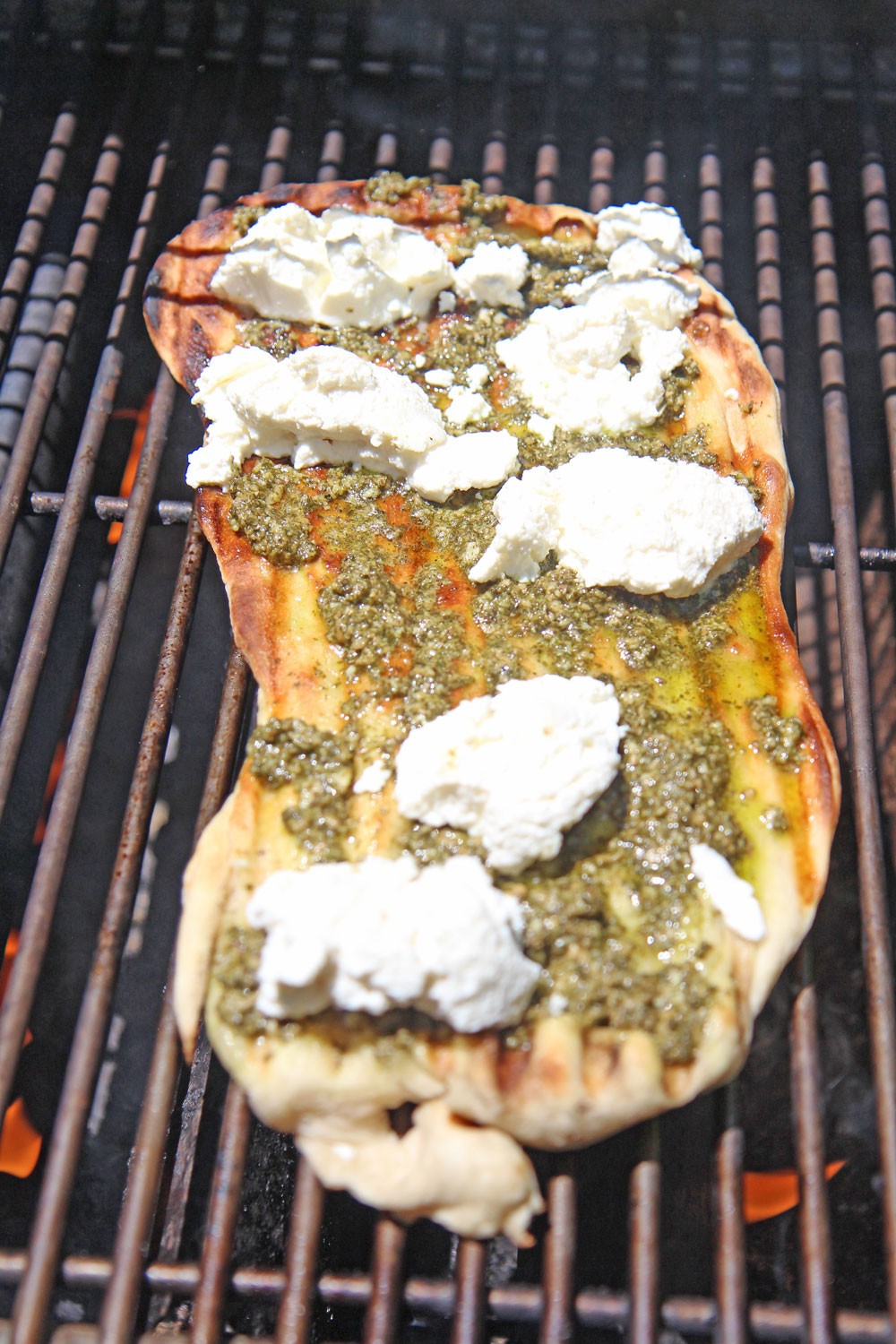 Easy Grilled Pesto Pizza Recipe. This is so easy to make. Grab pizza dough, pesto, riccota cheese, red pepper, and black pepper. You grill 2 minutes per side and dinner is ready. Happy grilling. www.ChopHappy.com #pizzarecipe #grillingrecipe