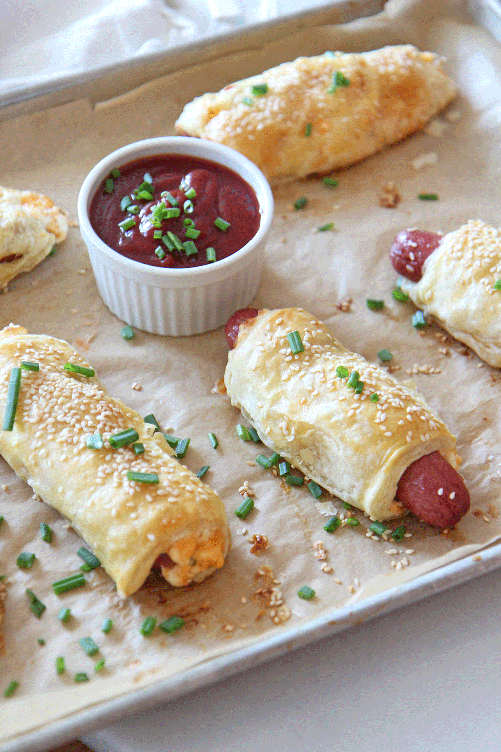 Cheesy Pigs In A Blankets For Dinner. Puff pastry, hot dogs, cream cheese, scallions, cheddar, and pantry ingredients is what you need for this recipe. Pigs in a blanket are a holiday celebration meal and now dinner. Happy Sheet Pan Cooking! #sheetpanrecipes #pigsinablanket